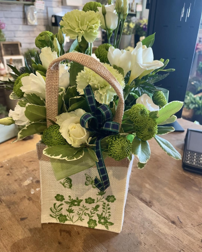 Neutral handtied - A delightful, nature-inspired arrangement presented in a rustic woven gift bag, bringing a touch of countryside elegance to any space. Soft neutral tones are beautifully complemented by vibrant green textures, creating a crisp and refreshing look. Accented with a classic ribbon and lush foliage, this design feels both wholesome and refined. Perfect for thoughtful gifting, it offers a sense of calm, freshness, and understated beauty.