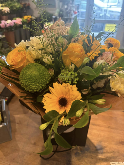 Golden Meadow Glow - A radiant and uplifting arrangement inspired by sunlit fields and warm, carefree days. Rich golden tones take center stage, beautifully balanced with fresh greenery and soft neutral accents. The natural, slightly wild styling gives it an airy, just-picked feel, while the structured presentation keeps it refined and gift-ready. Perfect for brightening someone’s day or celebrating joyful moments, this design brings warmth, positivity, and a touch of sunshine into any space.